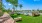 Outdoor fitness area with grass and kettle bells near pool with palm trees in the back