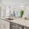 Large kitchen island with white cabinets and stainless steel dishwasher and sink 