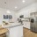 Large kitchen island with bar seating and stainless steel appliance and white cabinetry in back 