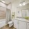 Bathroom with full tub and shower with large tiles and shower curtain and large mirror at vanity
