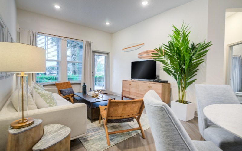 beautiful living room with large couch, tv, brown chairs, and a door to the outdoor patio